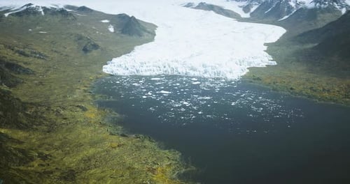 Glacier Calving Into a Serene Lake Surrounded By Rugged Mountains