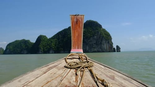 Shot of the front of a modest wooden boat sailing through Thailand's tropical waters.