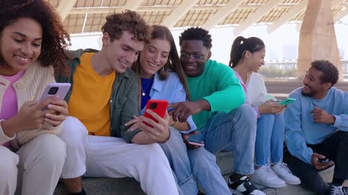 Friends Using Cell Phones Together Outdoors in City