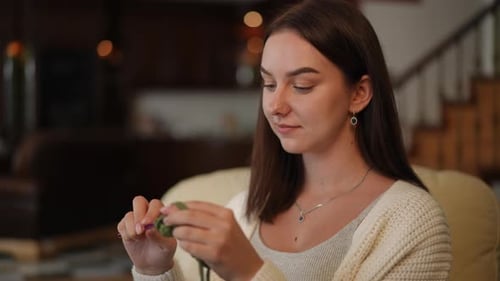 A Creative Woman Crocheting Brings a Cozy and Inviting Atmosphere to Home Spaces