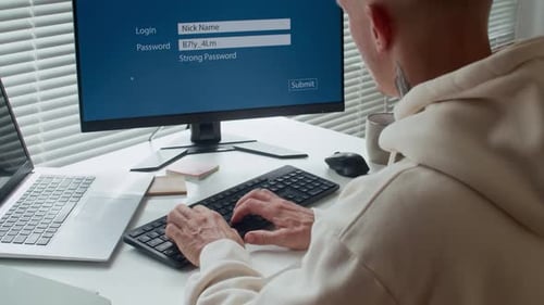 User Typing Password on Computer at Desk