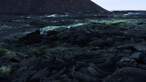 Solid black basalt lava field with sulfur vents rising steam, Iceland