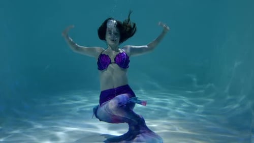 Schlanke, schöne Meerjungfrau, die Angst hat und unter Wasser davonschwimmt