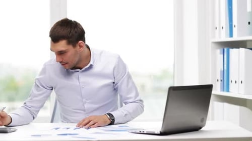 Man Working on Charts and Graphs in Office