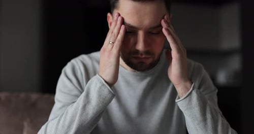 Man with Headache Rubbing Temples Indoors