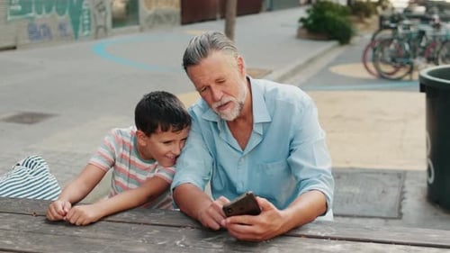 Grandfather and Child Using Phone Together Outdoors
