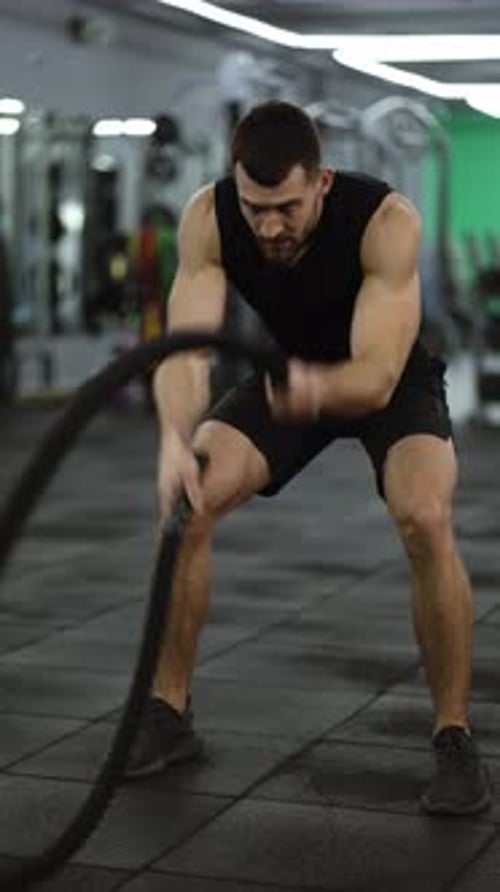 Attractive Muscular Man Working Out in the Gym Using Battle Ropes
