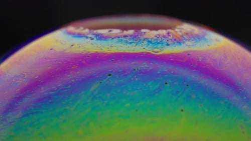 Vibrant close-up of colorful soap bubble with iridescent patterns on a black background