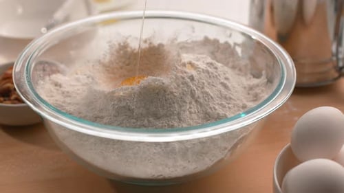 Egg Yolk Falling into Flour Bowl in Kitchen