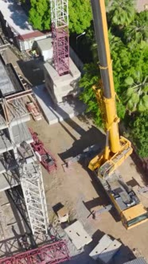 Vertical Video Skilled Workers Assembling A Tower Crane On A Busy Construction Site Captured