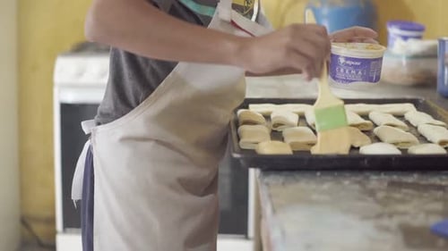 A pastry chef uses a brush to moisten dough with water or egg wash, ensuring an even browning during
