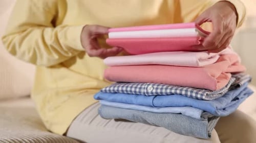 Woman sorting neatly folded stack of clothing