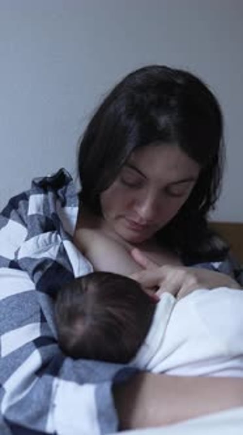Mother nursing her infant indoors in portrait orientation