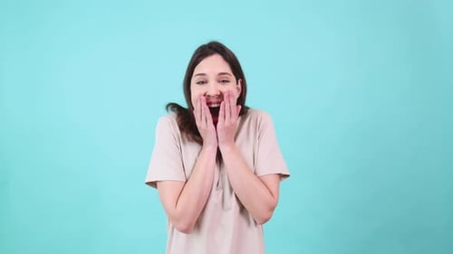 Mujer emocionada expresando felicidad sobre fondo turquesa
