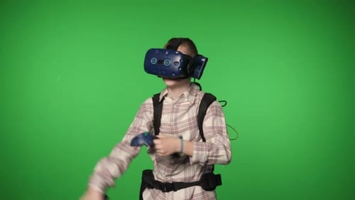 A Boy in Virtual Reality Headset is Playing a Video Game on a Green Background