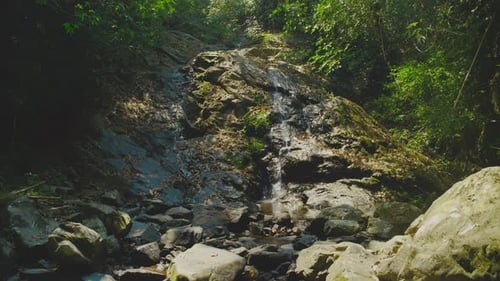 Ein ruhiger Wasserfall stürzt das felsige Gelände hinunter, umgeben von üppigem Grün im Nationalpark Khao Sok