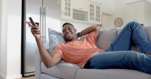 Man Relaxing on Couch with TV Remote