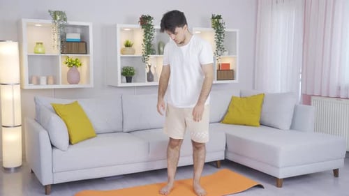 Young Adult Man Stretches on Yoga Mat Indoors
