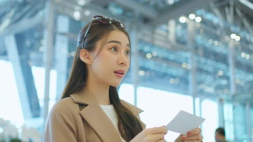 Asian young woman passenger checking depature boarding pass in airport.