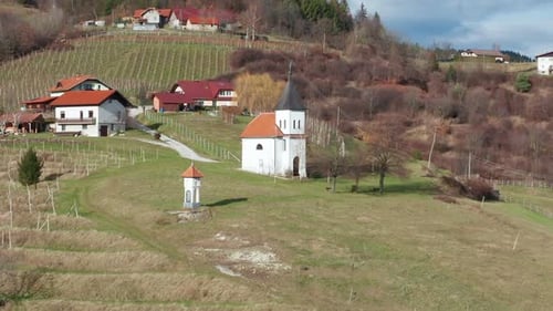 Scenic White Chapel Nestled Within Rolling Green European Hillside Vineyards