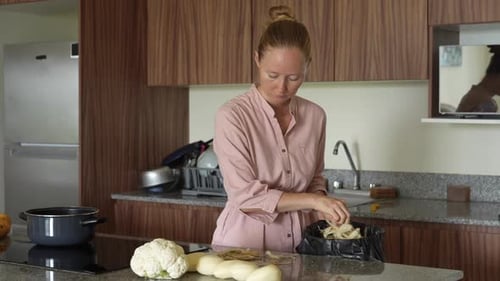 Woman Prepares Vegetables and Discards Scraps in Kitchen