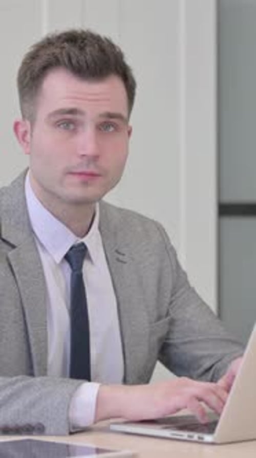 Smiling Young Man Working on Laptop at Desk
