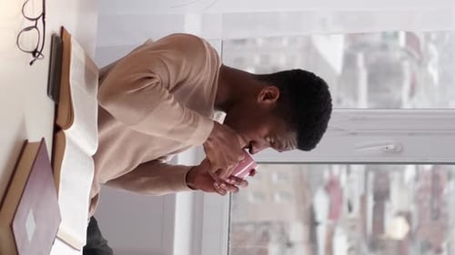 Man Drinking Coffee by the Apartment Window