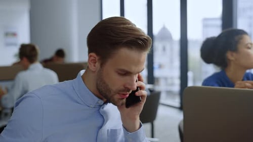 Homme d'affaires sérieux parlant d'un téléphone portable sur son lieu de travail. Professionnel masculin ayant un appel téléphonique