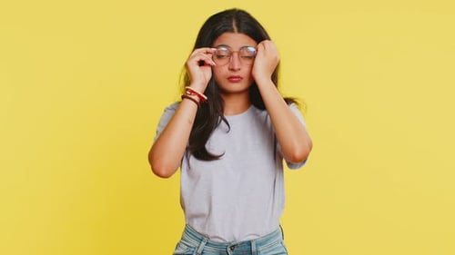Woman Removes Glasses and Rubs Tired Eyes