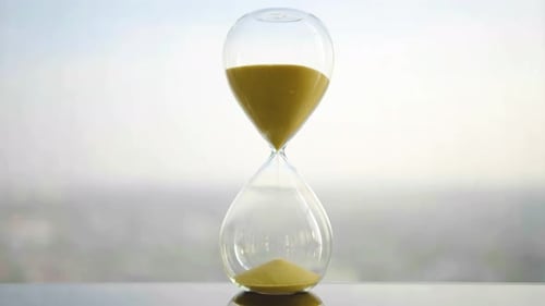 hourglass on table, sand flowing through the bulb of sandglass, time is money concept