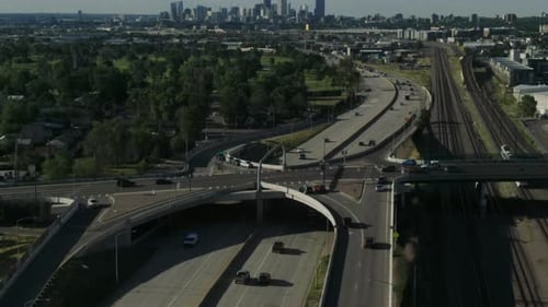Drone following tilt shot of cars driving over the highway towards the skyline of Denver.