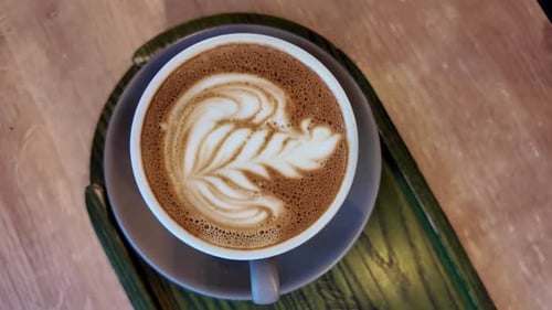 Close up big cup of cappuccino with coffee drawing art on top