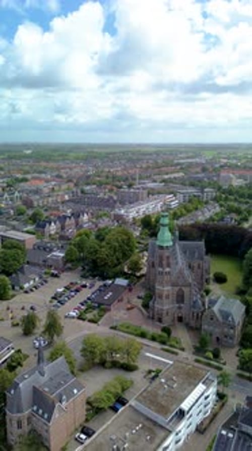 Aerial view of a historic church with a tall brick tower, surrounded by trees, houses, and streets