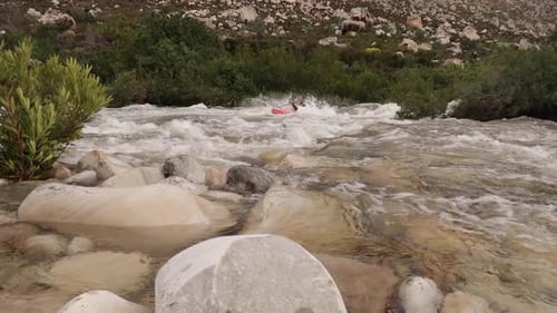 Aerial footage of white water kayaks paddling in the white water rapids on a freestone stream in the