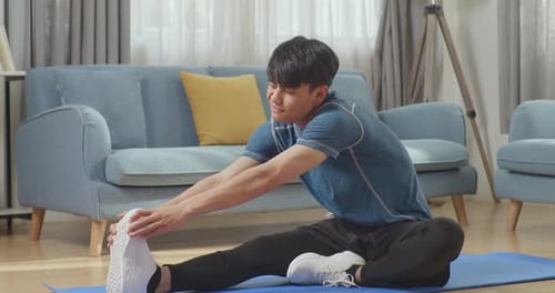 Young Adult Stretches Hamstrings on Yoga Mat