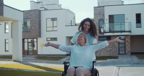 Caregiver Pushing Senior Woman in Wheelchair Outdoors