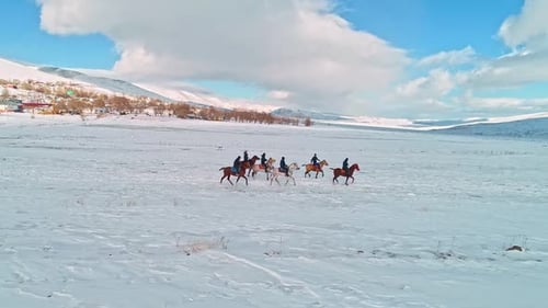 Group Horseback Riding Across Snowy Plain in Winter