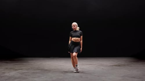 Alluring Young Woman Dancing in Studio Against Black Background