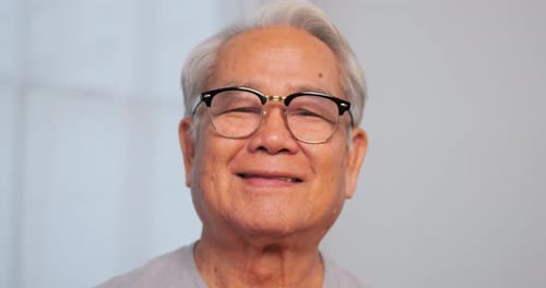 Close up, portrait of older man smiling and looking at the camera, isolated on white background.