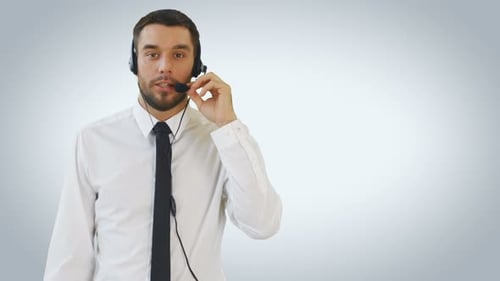 Mid Shot of a Handsome Customer Support Man Talking on a Headset with a Client. Shot on White Backg