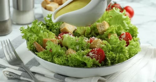Woman pouring sauce onto tasty salad with croutons at table, closeup