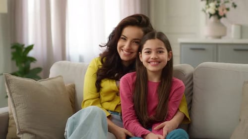 Smiling Mother and Daughter on Couch Together