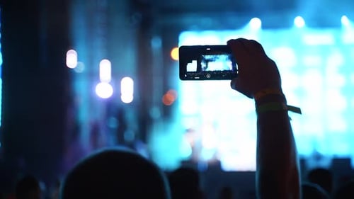 Close Up of Man Hands Silhouette Taking Photo or Recording Video of Live Music Concert with