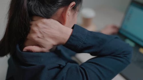 Tired female guest woman has neck pain working at computer sitting on sofa in office at night