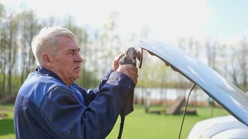 Der Mitarbeiter der Karosseriewerkstatt bearbeitet die Schweißnaht mit einem Winkelschleifer an einem ausgetauschten Autoteil