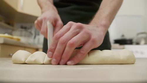 Person Cutting Dough in Kitchen with Scraper