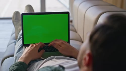 Man Lying on Couch Typing on Laptop