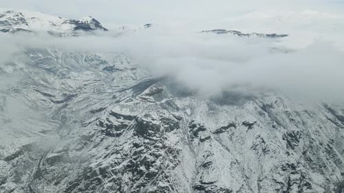Birdseye Flight Over Picturesque Cold Frosty Winter Landscape with Snow Covered Mountain Picks Fog