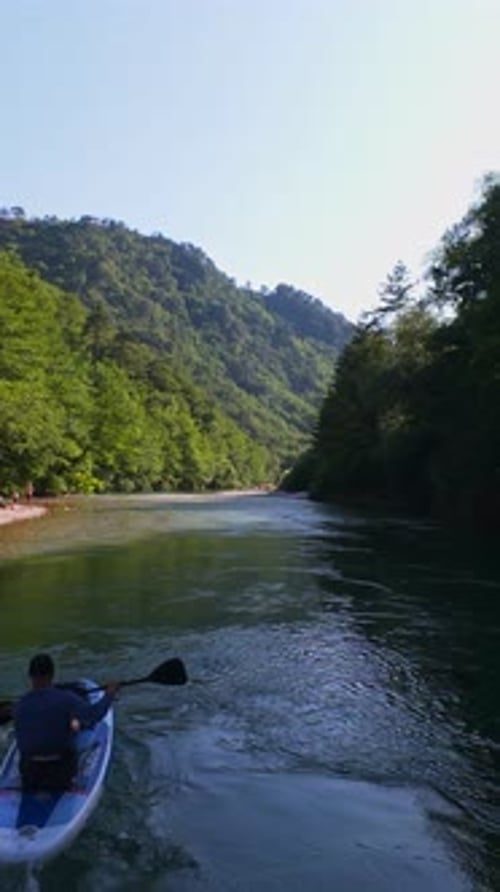 Vertical Video of FPV Drone Aerial of Friends Paddleboards Through a Shallow Crystal Clear River