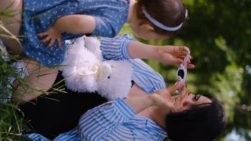 Mother and child together in the park outdoors, lying in the grass. Motherhood happiness concept. Da